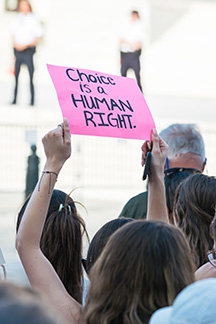 Protestor holding a pink sign that reads Choice is a Human Right