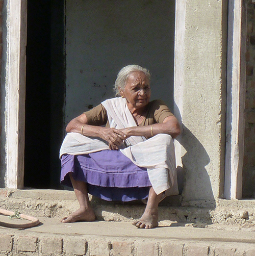 Older Indian woman sitting on a small wall