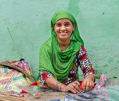 Indian woman in a green headscarf works with her hands.