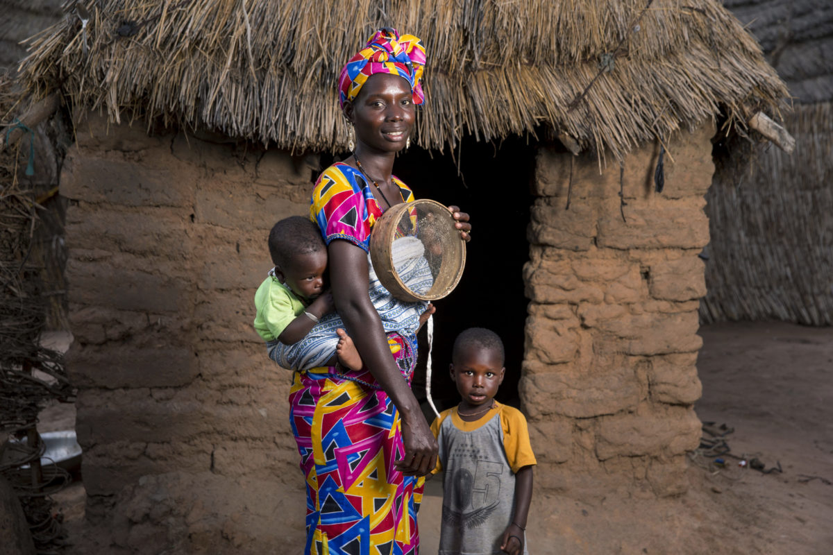 African woman standing with children in a bright dress