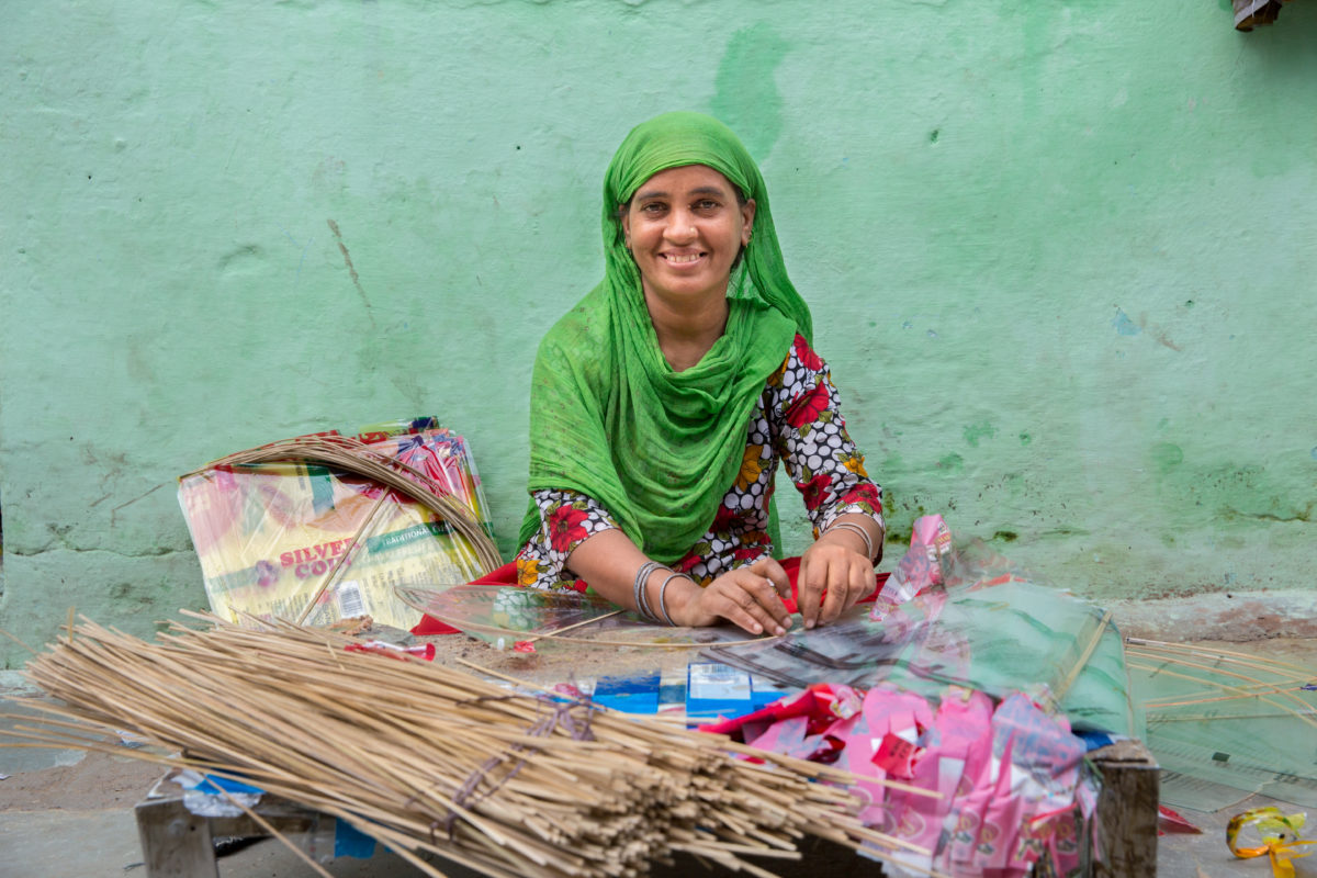 woman in green headscarf sitting and working with her hands