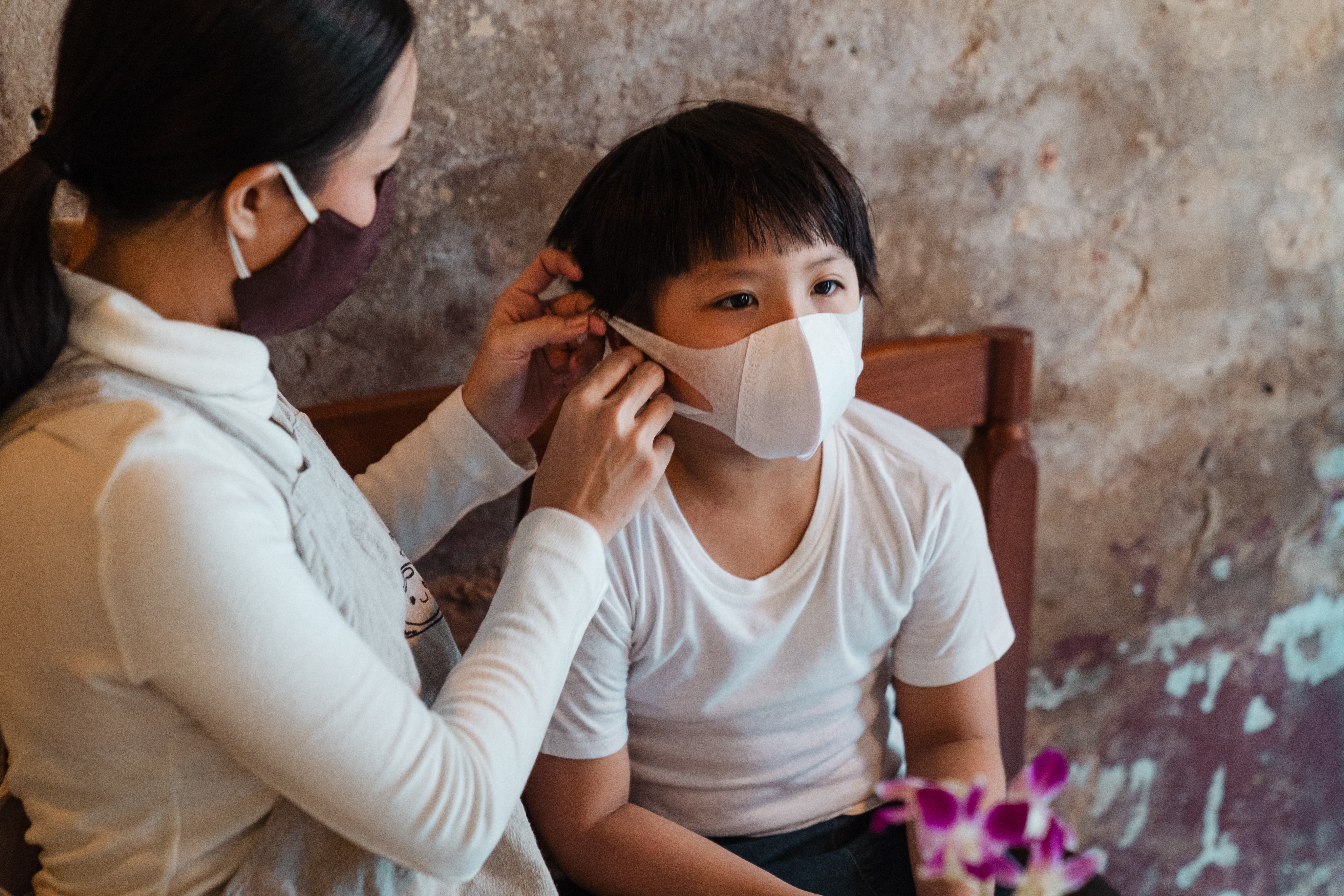 Mother adjusts child's mask