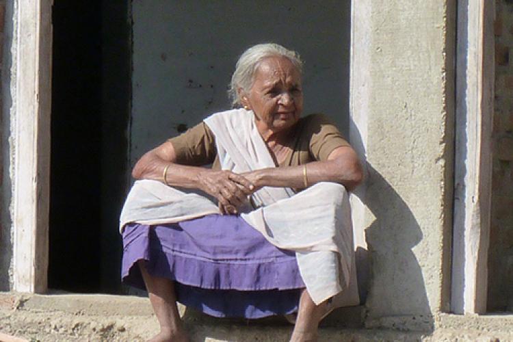 Older Indian woman sitting on a small wall