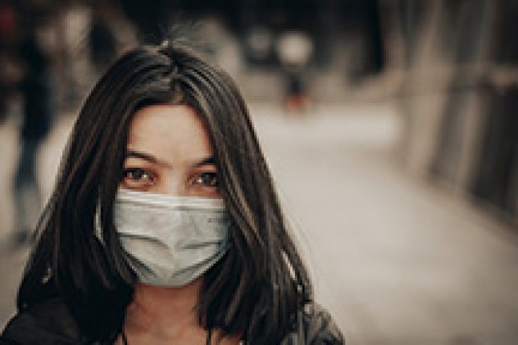 Dark haired young woman wearing a surgical mask.